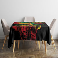 Black tablecloth with vibrant red, green, and yellow mural-style reggae print on tabletop