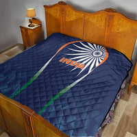 Blue India quilt with quilted pattern and sunburst logo on a bed
