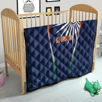 Blue India quilt blanket with sunburst logo and INDIA text, on crib mattress