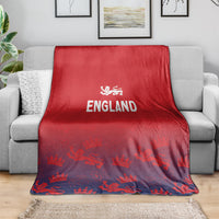 Red England blanket laid across gray sofa, England text and crown-and-lion motifs