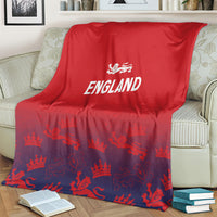 Red England blanket draped on cream-striped sofa, white England logo with crown-and-lion print