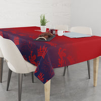 Red and navy king-crown patterned tablecloth on dining table with centerpiece.