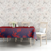 Red and navy crown-patterned tablecloth on dining table with cups and vase.