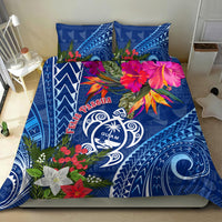 Blue bedding set on bed with Guam turtle emblem, poinsettia flowers, and tapa-style designs
