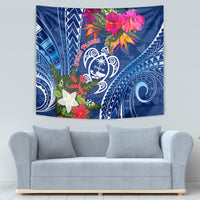 Blue tapestry on wall with white Guam turtle emblem, pink flowers, and blue tribal designs.