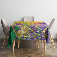 Mardi Gras tablecloth on dining table featuring green, purple, and gold watercolor swirl and beads
