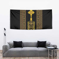 Black wall tapestry with gold Ethiopian-inspired center cross and geometric pattern.