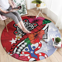 Red round rug with black tribal graphic, blue-and-white figures, and orange flower accents.