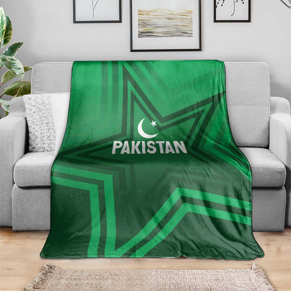 Green Pakistan sports blanket spread on gray sofa, star-and-crescent logo in center