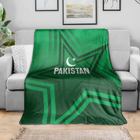 Green Pakistan sports blanket spread on gray sofa, star-and-crescent logo in center