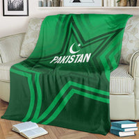 Green Pakistan sports blanket with large star pattern and crescent logo, on armchair