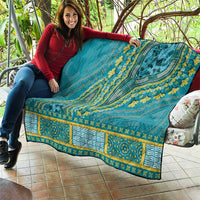 Teal dashiki-style quilt draped over seating with yellow ornamental motif border