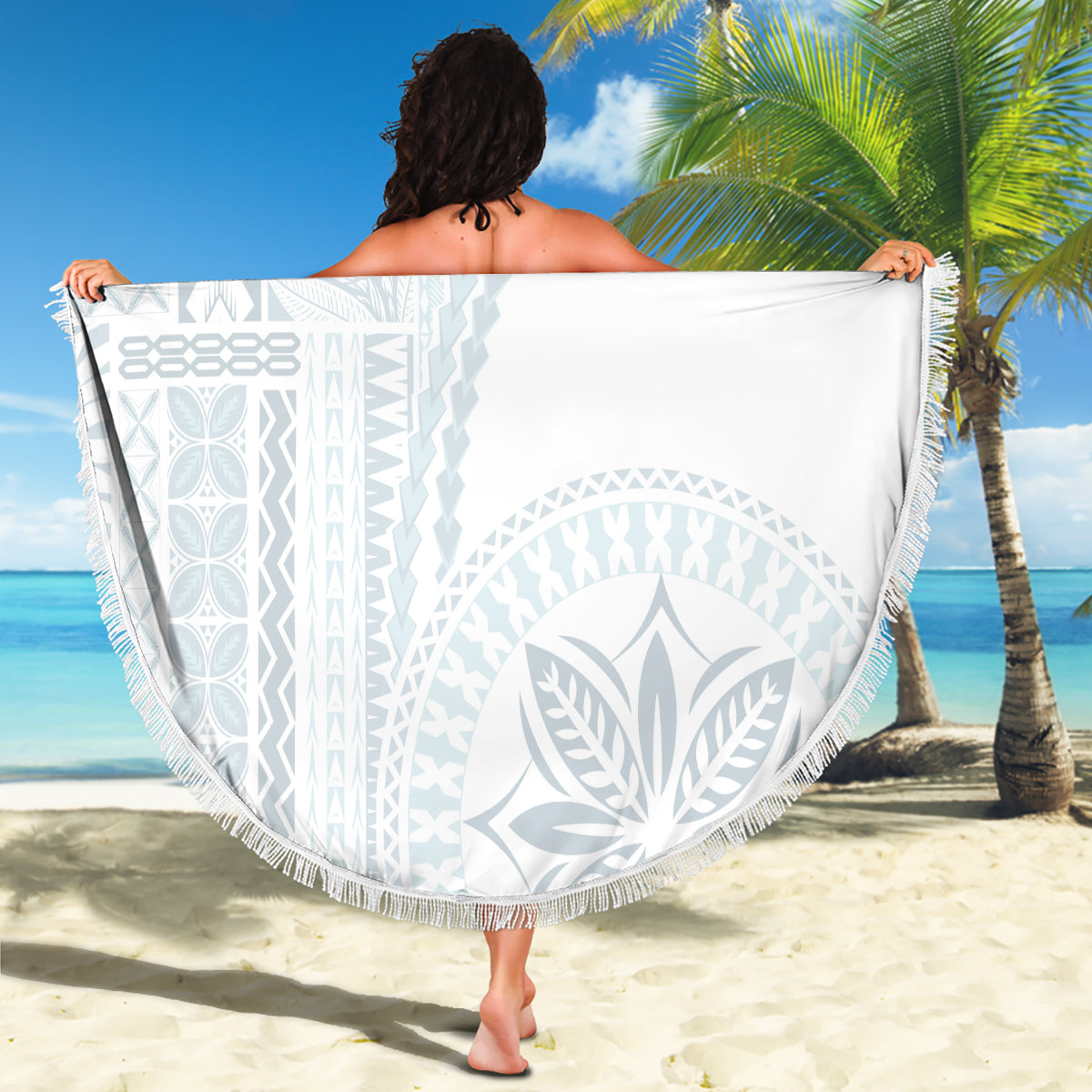 Beach blanket held up: round white fabric with light blue leaf and geometric design, fringe