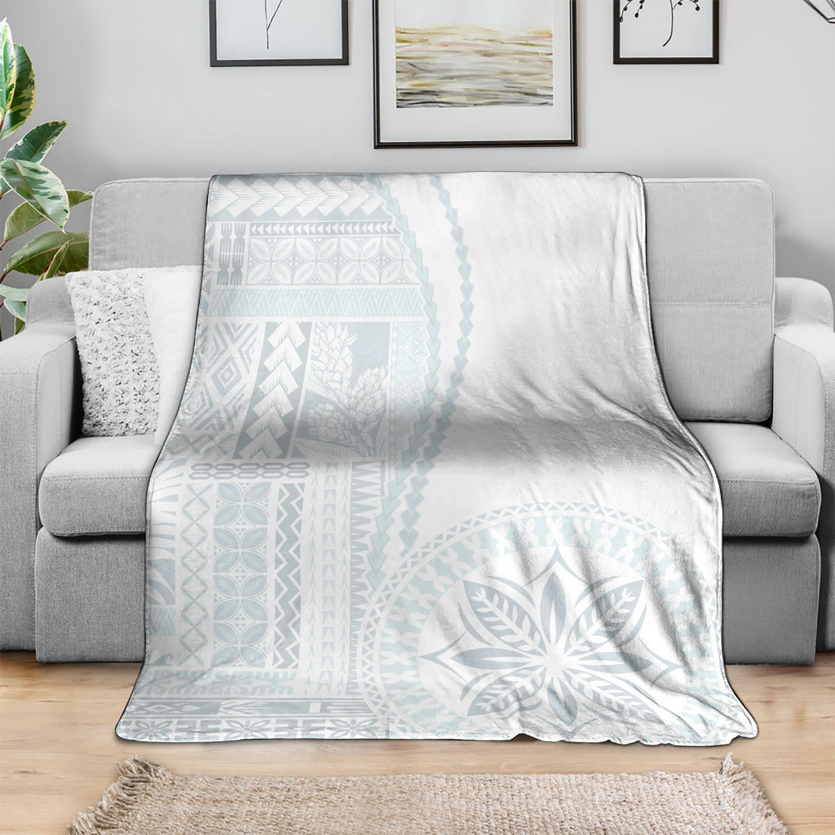 White and light-blue patterned throw blanket folded on a sofa.