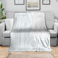White and light-blue patterned throw blanket folded on a sofa.