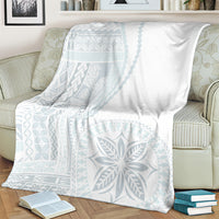 White blanket with light-blue ornamental motif, spread across an armchair.