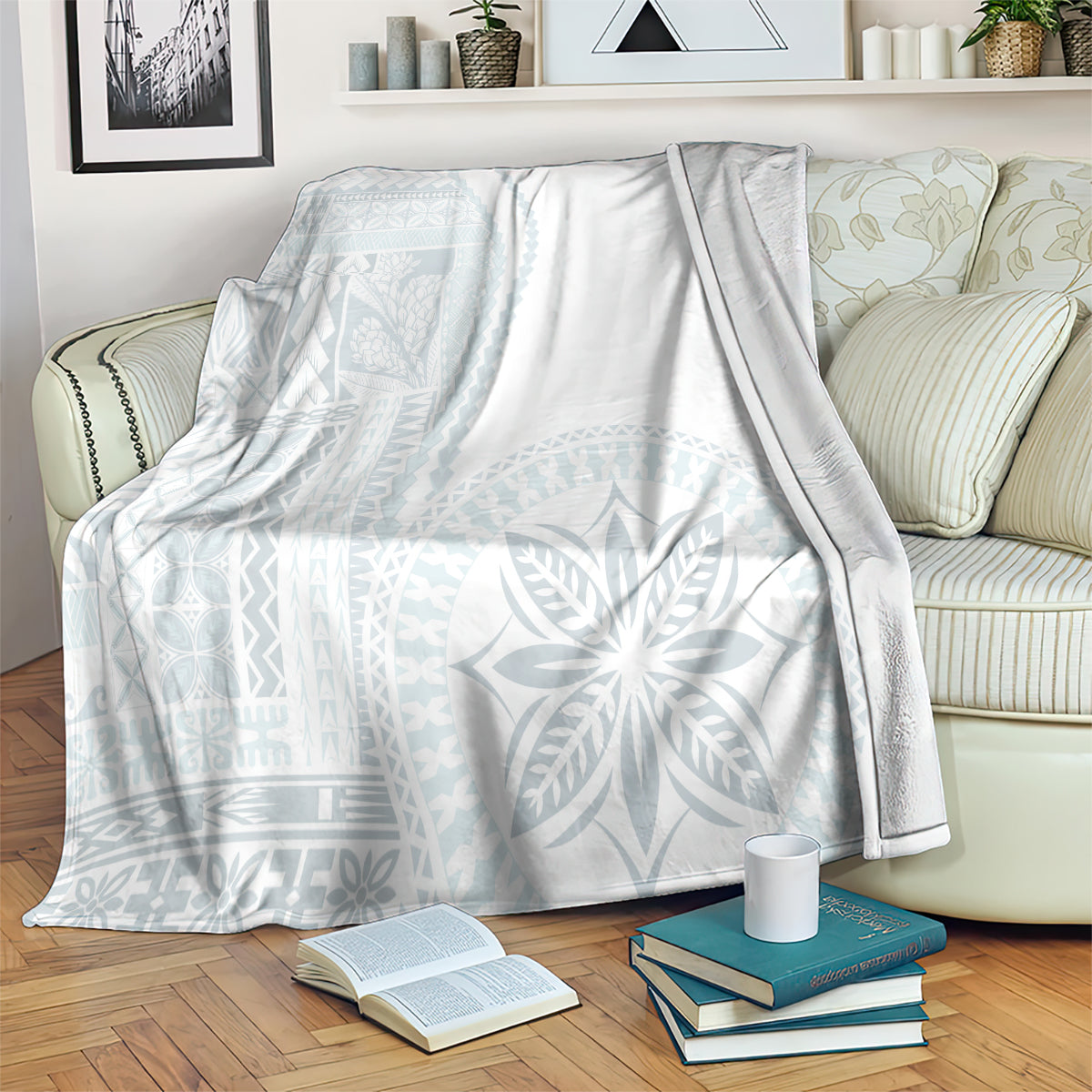 White and light-blue patterned blanket covering a couch, with folded books nearby.