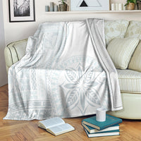 White and light-blue patterned blanket covering a couch, with folded books nearby.