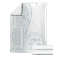 White blanket with light-blue patterned panels, shown with folded matching linens.