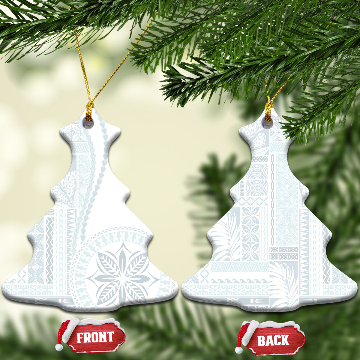 Two white ceramic bell-shaped ornaments with blue patterned siapo design hanging on gold cord.