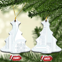 Two white ceramic bell-shaped ornaments with blue patterned siapo design hanging on gold cord.