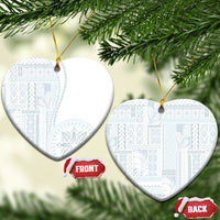 White ceramic heart-shaped ornament with blue patterned siapo design hanging on gold cord.