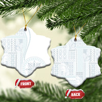 White ceramic star-shaped ornament with blue patterned siapo design hanging on gold cord.