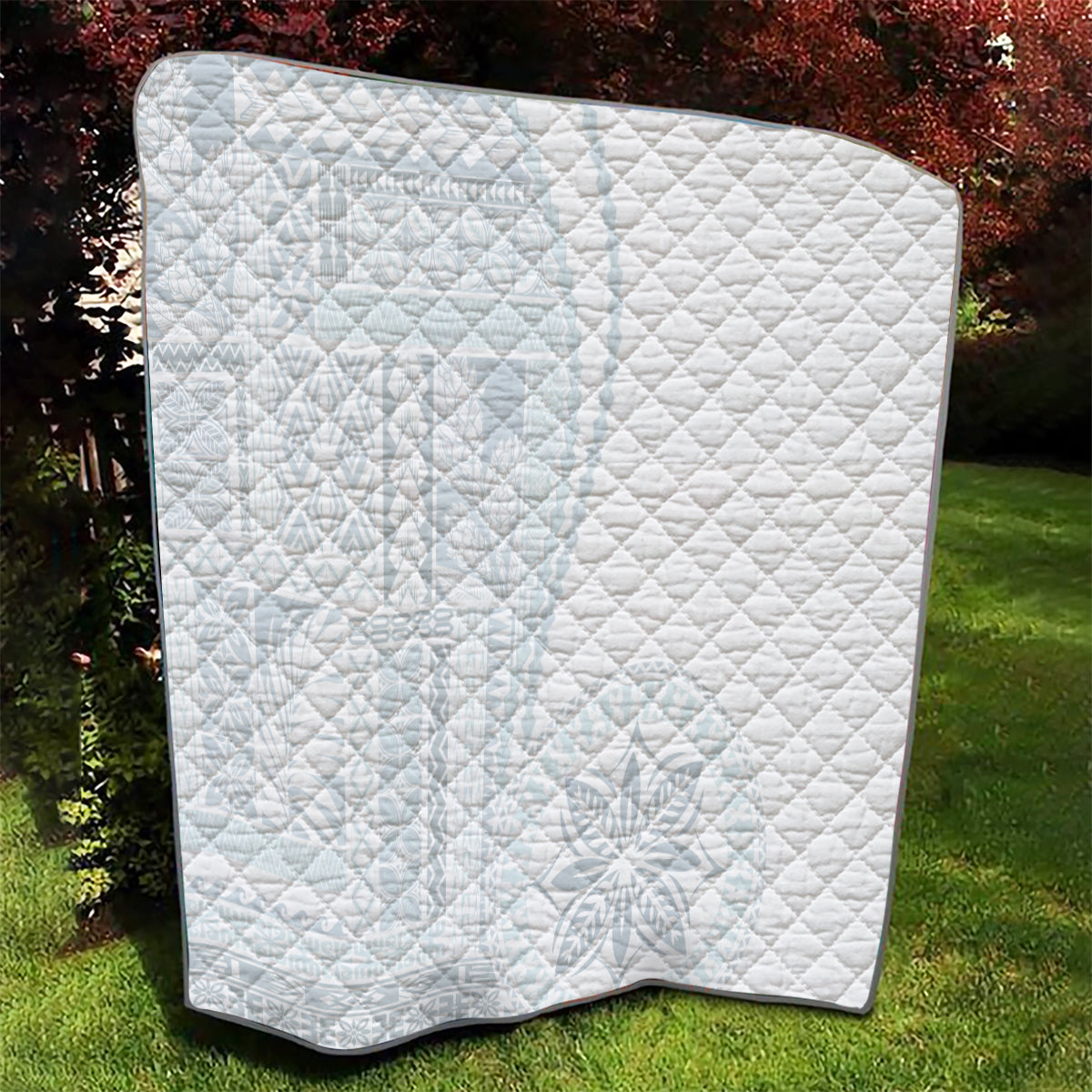 White diamond-quilted blanket with dark-trim edge, laid flat outdoors