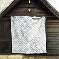 White quilt with diamond stitching and dark border trim, displayed on wall