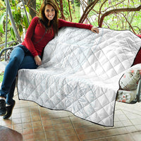 White quilted blanket with diamond pattern and dark trim, draped over couch