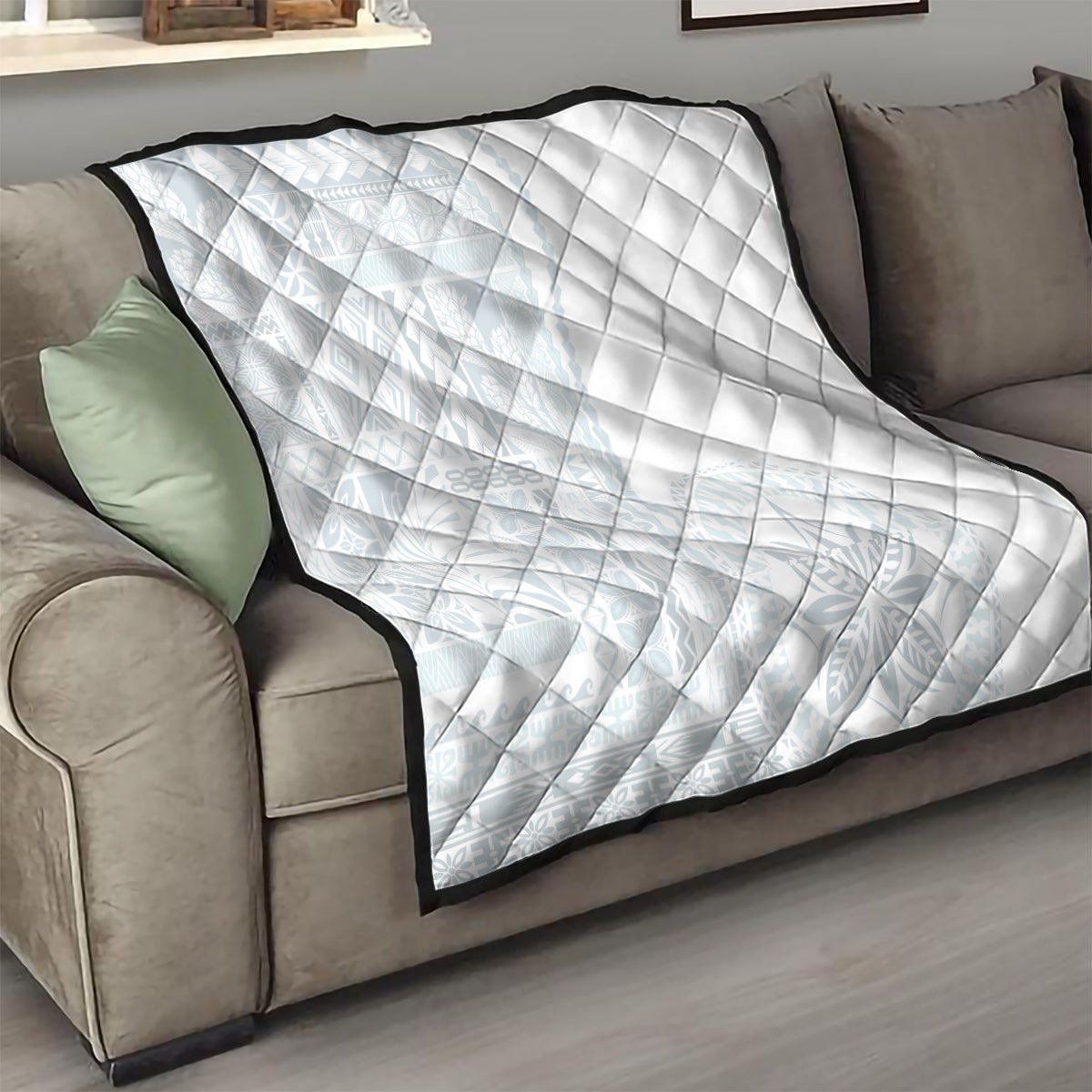 White quilt with diamond quilting and dark border, folded on sofa