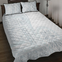 White quilt bed with two pillow shams featuring black piping and light blue diamond grid