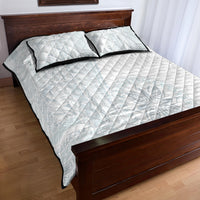 White quilt bed set with two pillow shams and black piping over a subtle geometric motif