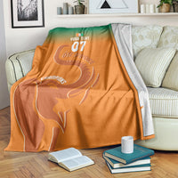 Custom football blanket draped on sofa, orange-to-green with elephant and Champions text