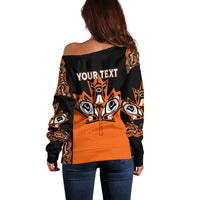 Black and orange off-shoulder sweater with 'Your Text' back graphic and tribal eye motifs
