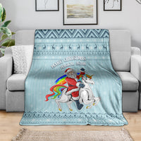 Turquoise fleece-style Christmas blanket draped on couch, unicorn and rainbow print