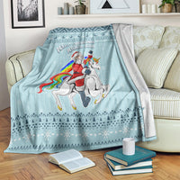 Turquoise Christmas blanket over armchair with unicorn graphic and festive patterns