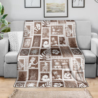 Brown patchwork blanket draped over a sofa, featuring square tropical and seasonal icons