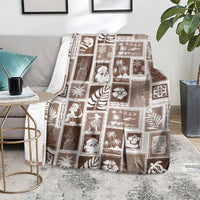 Brown patchwork blanket spread on a sofa, showing white square motifs and icons
