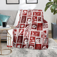 Red patchwork Christmas blanket folded on sofa, grid of festive icons and palm motifs