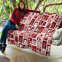 Red patchwork quilt with white holiday square designs spread on patio seating