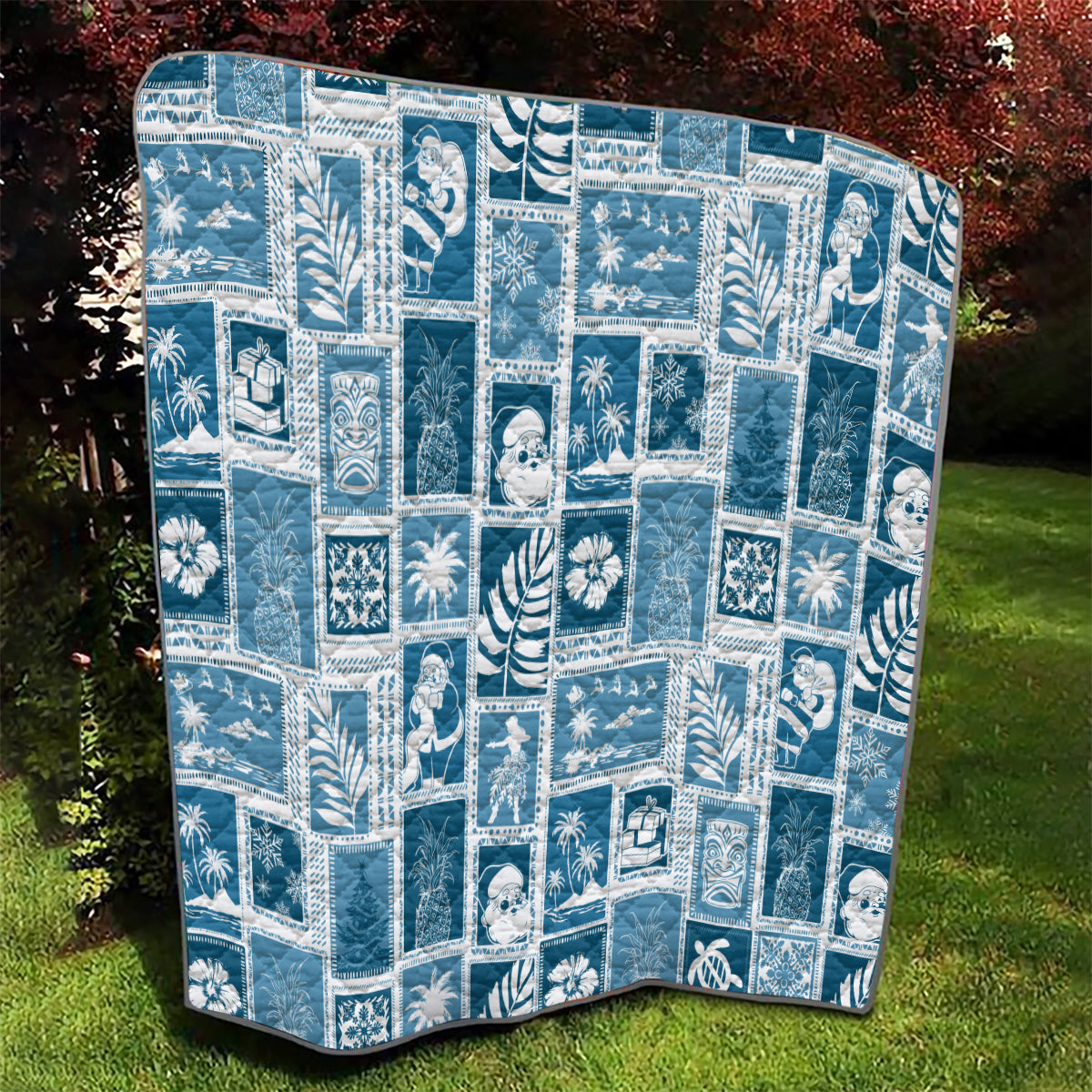Aquamarine quilt spread on grass, white patchwork grid with holiday motifs and border.