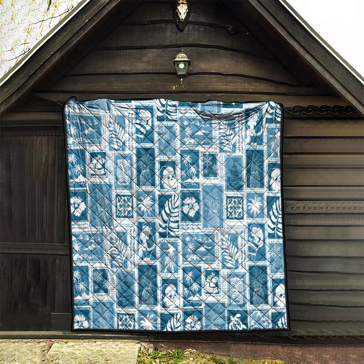 Aquamarine quilt hanging in wooden shed, white patchwork grid and stitched edge border.