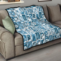 Aquamarine quilt blanket on sofa, white patchwork squares with holiday motifs.