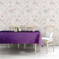 Purple confetti-dotted tablecloth on a long table with a simple centerpiece.