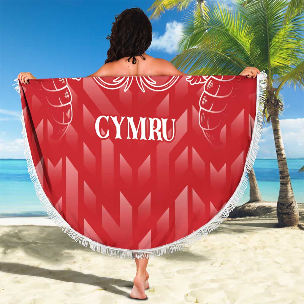 Red round beach blanket with white fringe, dragon crest and CYMRU lettering, held up