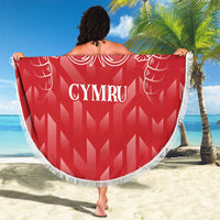 Red round beach blanket with white fringe, dragon crest and CYMRU lettering, held up