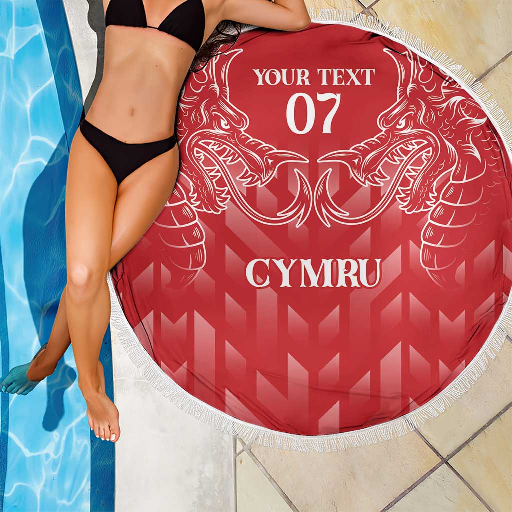 Red round beach blanket with white fringe, dragon crest and CYMRU lettering, close-up