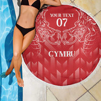 Red round beach blanket with white fringe, dragon crest and CYMRU lettering, close-up