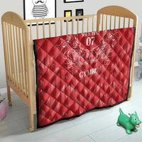 Red quilt on wooden baby bed frame, diamond quilting with white dragon crest and CYMRU